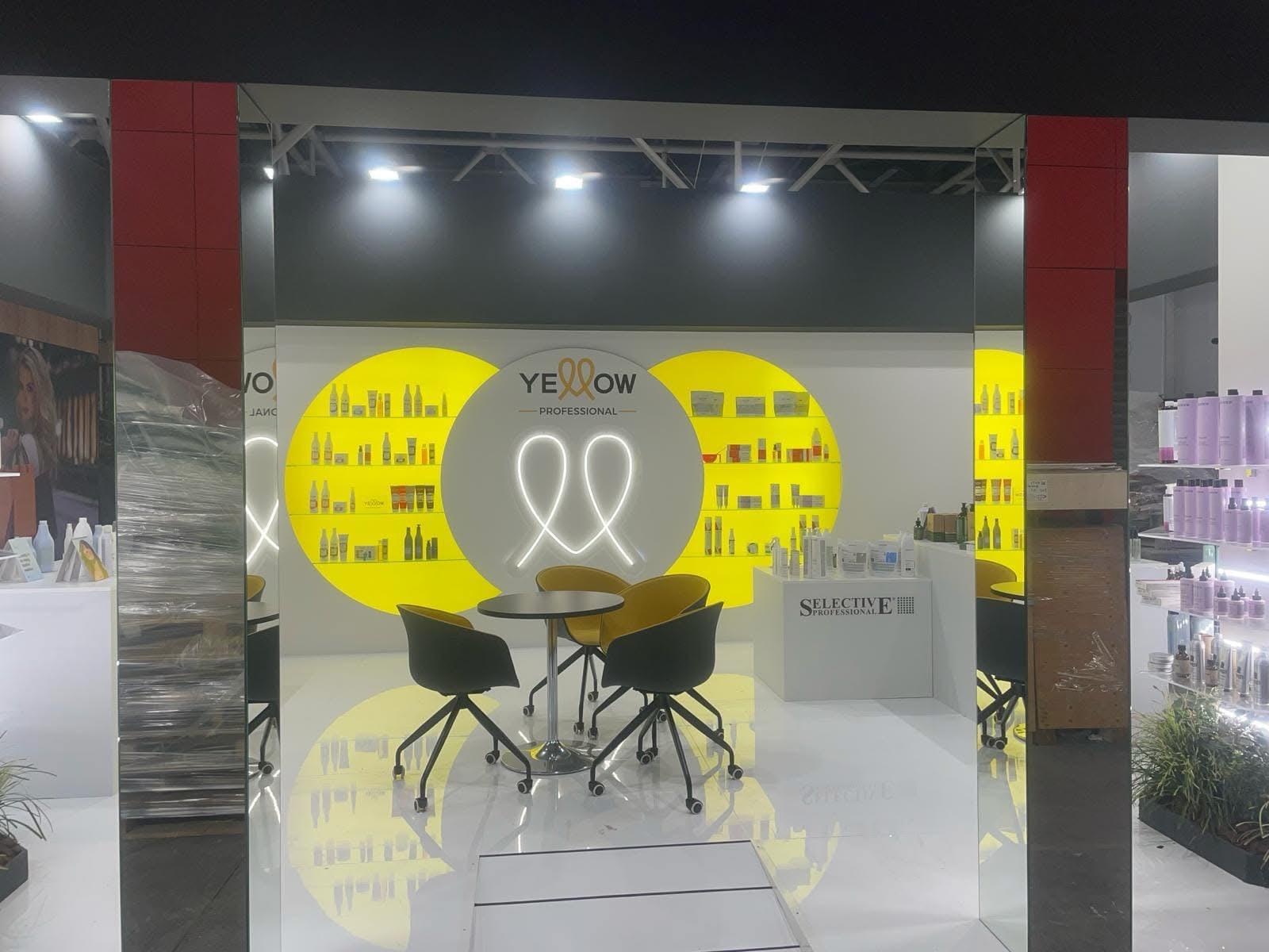 Stand Yellow Professional con display circolare e prodotti esposti